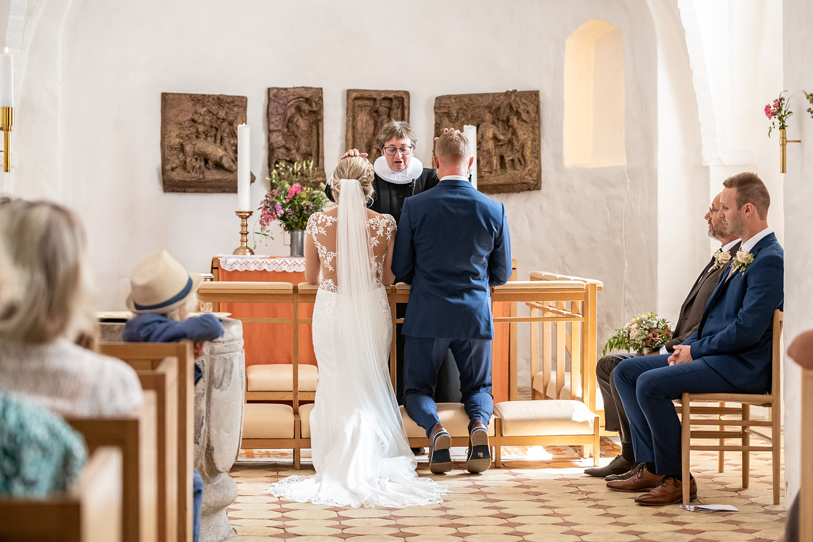 Bryllupsbillede af brudepar der bliver viet i kirken af præst